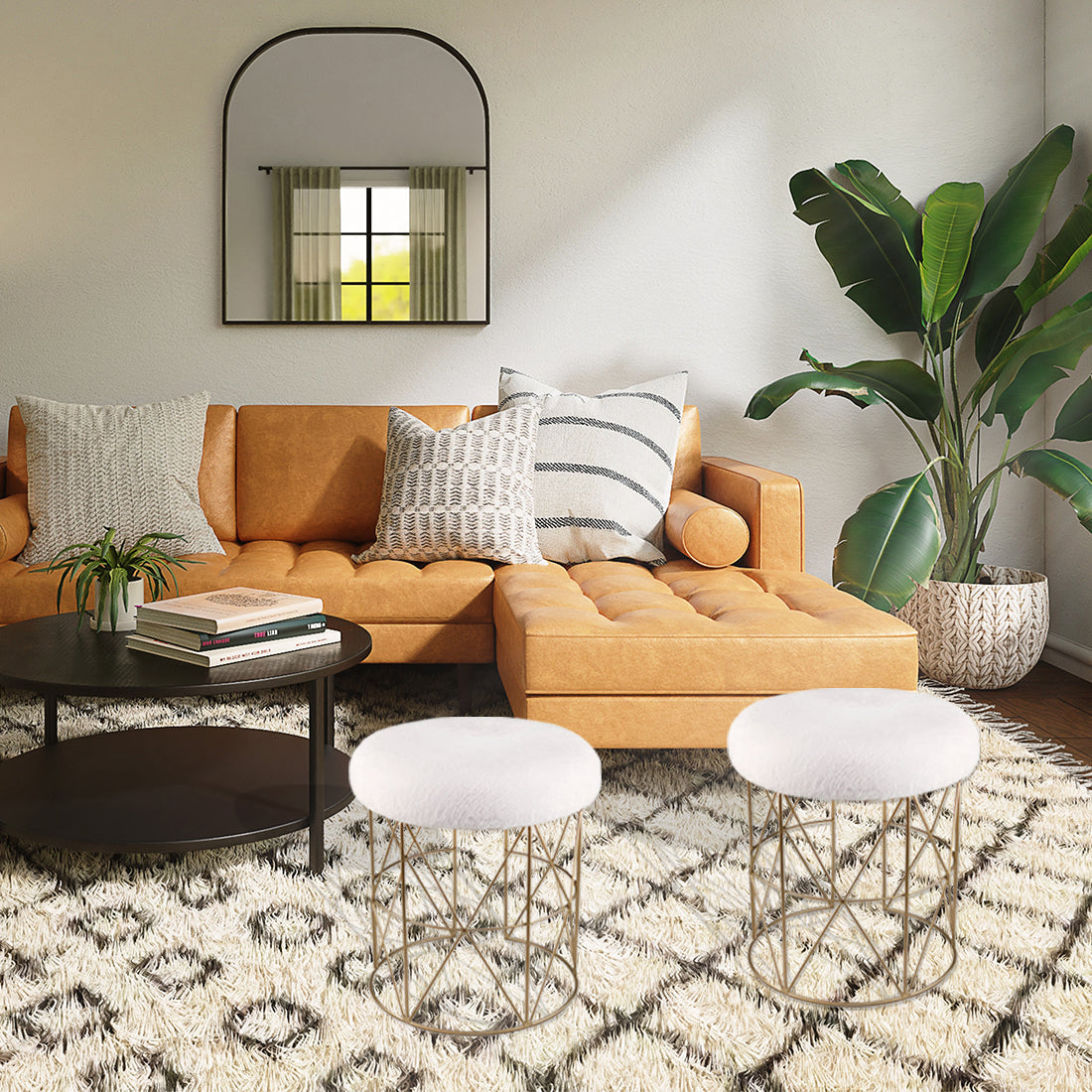 Modern living room with a mustard yellow sectional sofa, patterned area rug, round coffee table, minimalist stools, wall mirror, and a large indoor plant creating a warm and stylish interior.