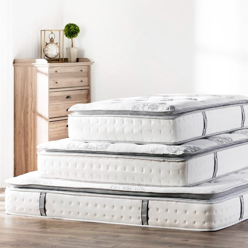 Stacked mattresses in different thicknesses displayed in a bedroom setting, showcasing layered comfort and supportive mattress design.